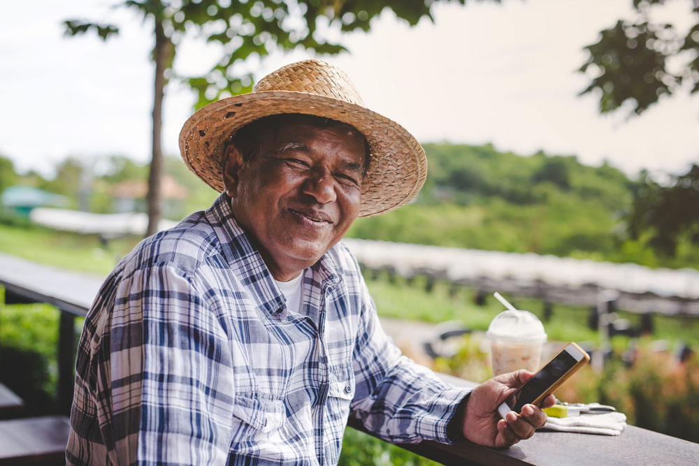 An Asian senior man is wearing a hat and smiling, happy while sitting in the garden.